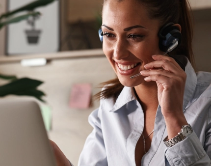 representante-servicio-al-cliente-feliz-hablando-cliente-mientras-usa-computadora-portatil-oficina
